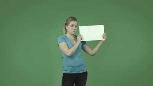 caucasian casual blond girl isolated on green upset with blank sign