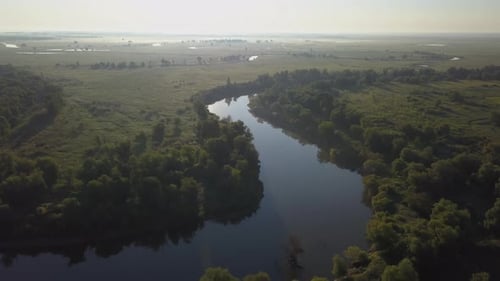 Aerial view of the green meadow with river