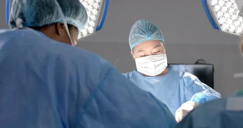 Diverse female surgeons operating on patient in operating theatre, slow motion