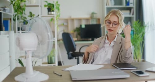Overheated Woman Fanning Shirt in Hot Office