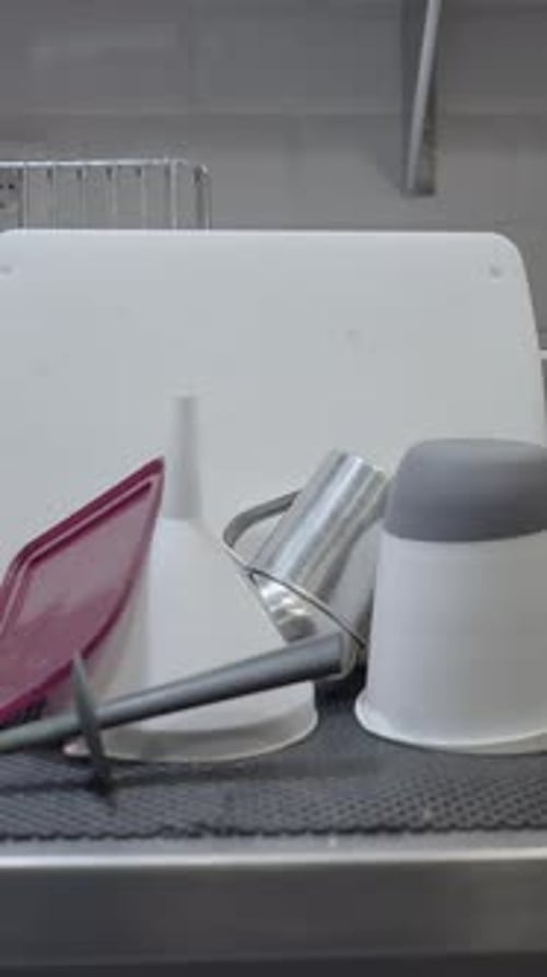 Pan of Clean Dishes Drying Beside Sink in Restaurant Kitchen