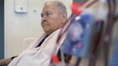 Senior Woman Sitting in Hospital with Medical Equipment