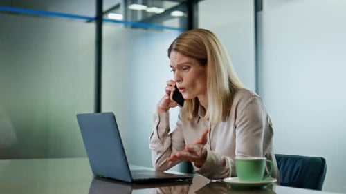 Woman Talking on Phone at Desk with Laptop