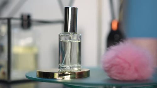 Closeup Cologne Bottle and Pink Fluffy Ball Spinning in Slow Motion on Glass Tray