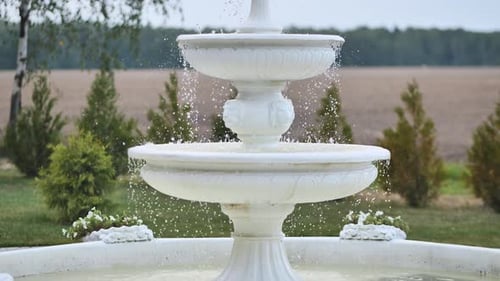 Dekorativer weißer Springbrunnen vor dem Hintergrund der Natur