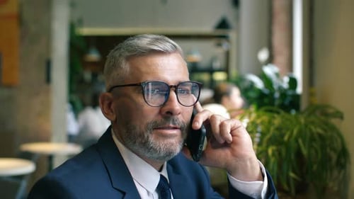 Senior Entrepreneur Discussing Business during Phone Call in Cafe