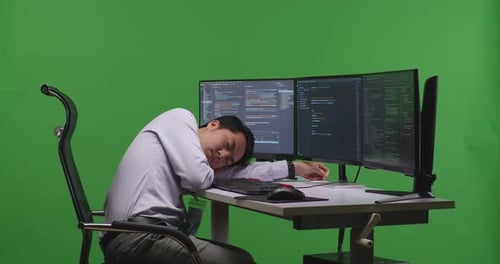 Tired Man Developer Sleeping While Write Code With Multiple Computer Screens In Green Screen Studio