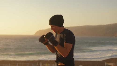 Determined Fighter Hitting By Hands in Air Near Ocean at Sunset