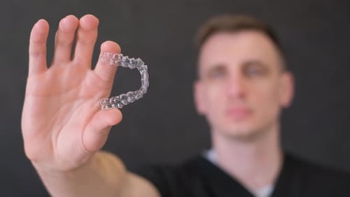 Closeup a Dentist Demonstrates Modern Aligners for Straightening Teeth