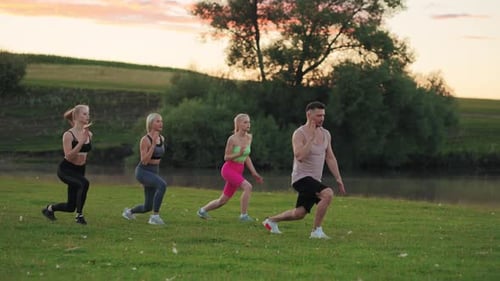 Fitness Group Performs Lunges Outdoors at Sunrise