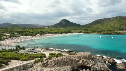 Aerial rising shot revealing beautiful sandy beach with plenty of tourists with blue sea and natural