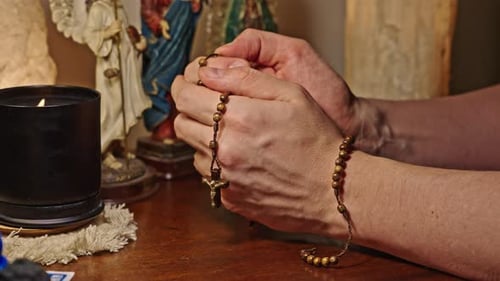 Hands Holding Rosary Beads in Prayerful Setting