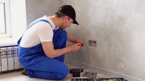 Professional Electrician Working on a Home Electrical System He is Installing a Wall Socket