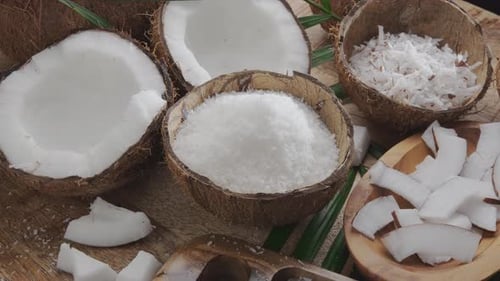 Frisch geöffnete Kokosnüsse zusammen mit Kokosflocken; Scheiben und Kokosnussblätter drehen sich langsam auf einem