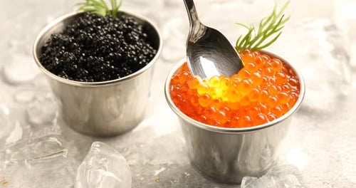 Taking delicious red caviar with spoon from bowl at grey table, closeup