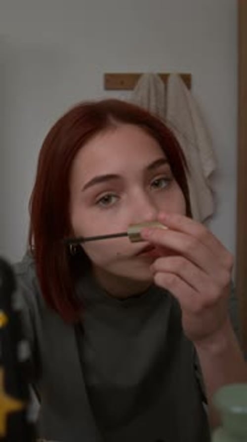 Applying Mascara on Eyelashes and Scrolling through Posts in Smartphone