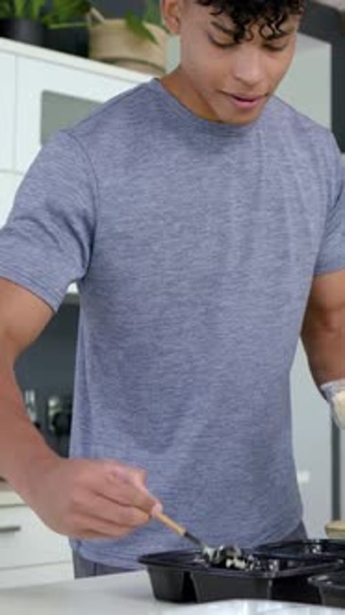 Vidéo verticale : saisissant un bol en verre, un homme met du riz dans des plateaux noirs à la cuisine pour les repas, une cuillère