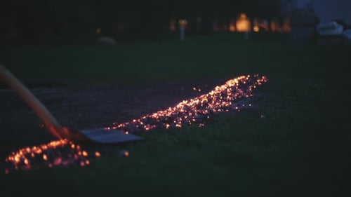 Spreading Glowing Embers With Tool at Night