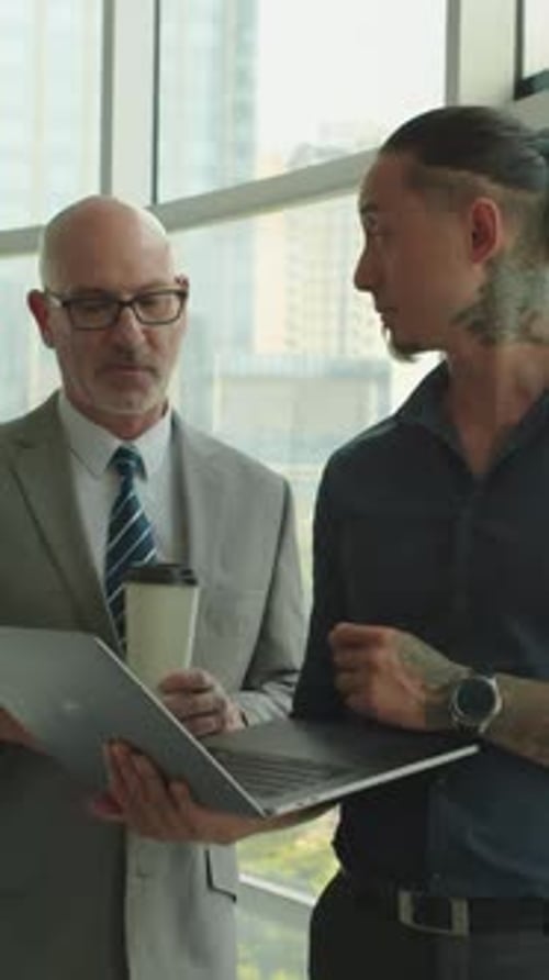 Men Reviewing Laptop in a Modern Office