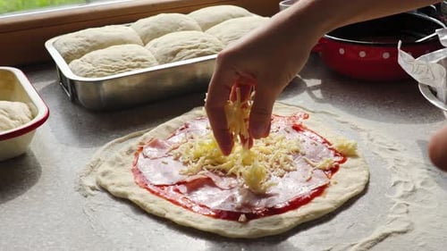 Primer plano del chef poniendo queso rallado sobre la masa de pizza con salsa de tomate. Proceso de elaboración de tr