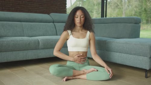 Young Woman Meditating in Lotus Position Indoors