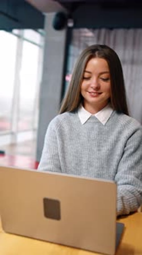Smiling Woman Working on Laptop at Table