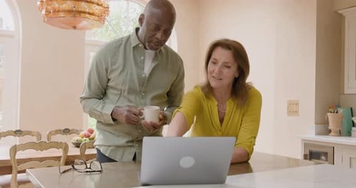 Couple using laptop together in bright kitchen