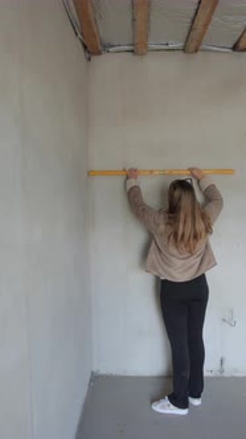 Vertical Video Young Adult Woman Checking Wall Surface with Yellow Level