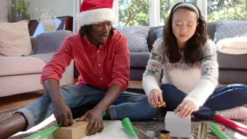 Couple Wrapping Christmas Gifts in Living Room