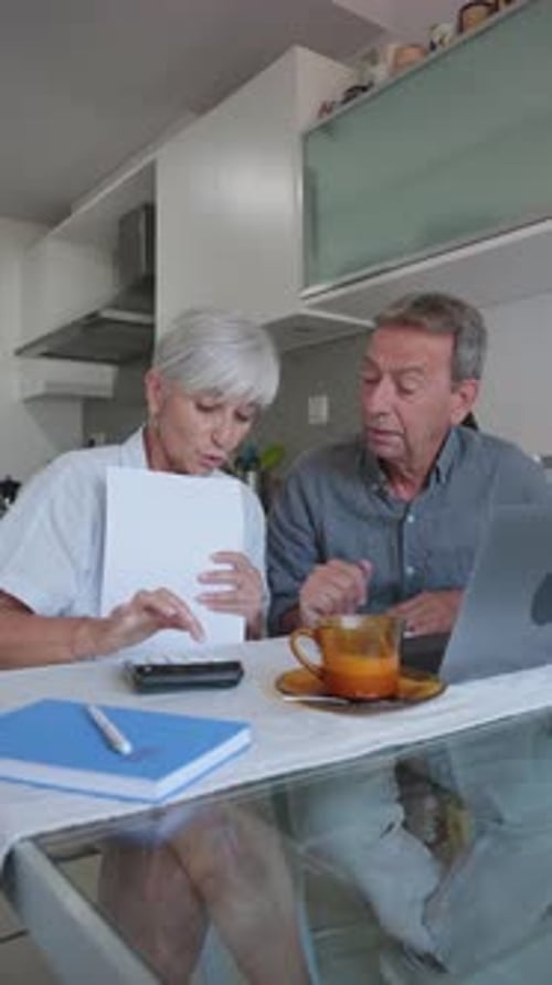 Mature Couple Discuss Finances at Kitchen Table