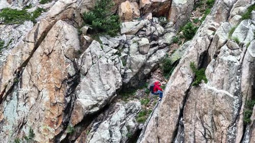 Mountaineer Slowly Climbs a Steep Rock Face in the Mountains