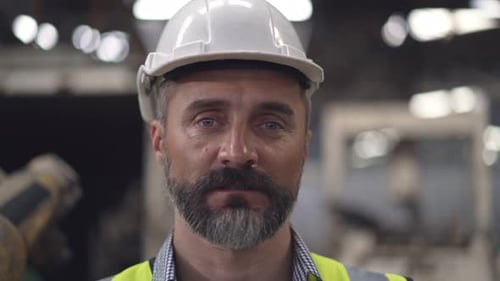 Porträt eines Fabrikvorarbeiters in Schutzkleidung, der in die Kamera blickt