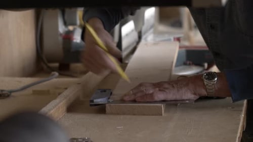 Carpenter Marking Plank of Wood with Pencil in Workshop 70s