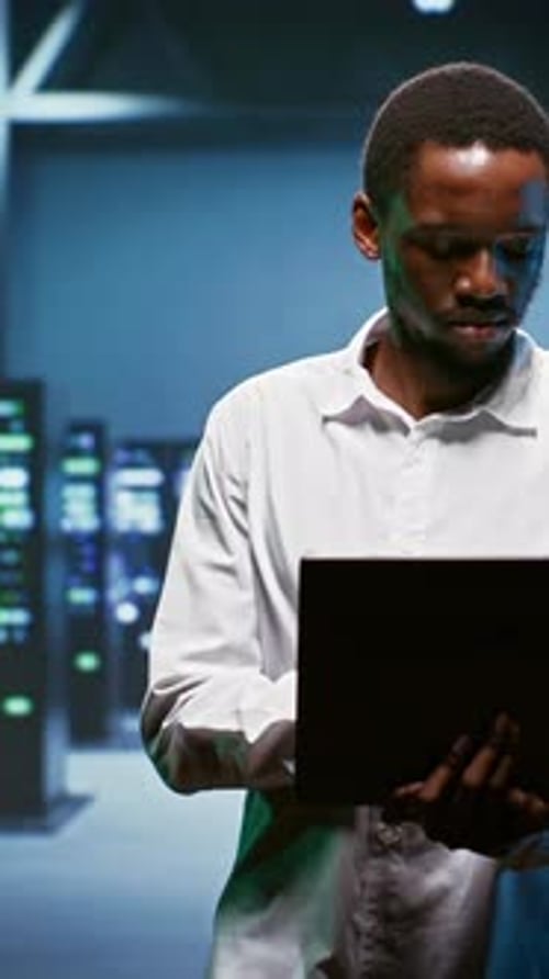 Adult Technician Smiling in Server Room at Night