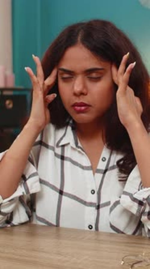 Woman removes glasses and rubs head