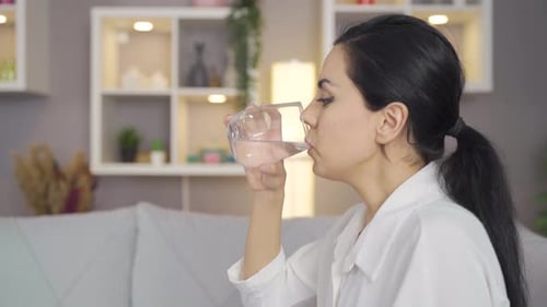 Mujer bebiendo agua en casa.