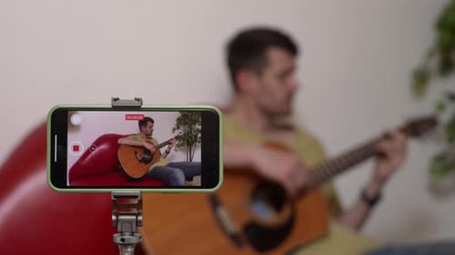 Young Adult Plays Guitar While Recording Video