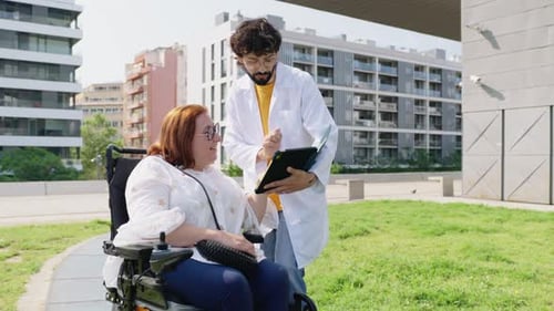 Arzt erklärt Frau im Rollstuhl medizinische Informationen