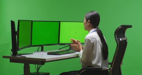 Seitenansicht einer asiatischen Frau beim Video mit einem nachgebildeten Computerbildschirm im Greenscreen-Studio
