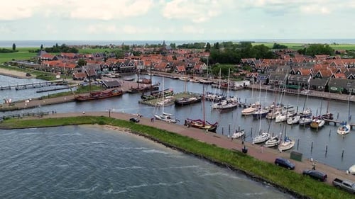 Aerial view of a charming Dutch harbor town with traditional red-roofed houses, moored sailboats