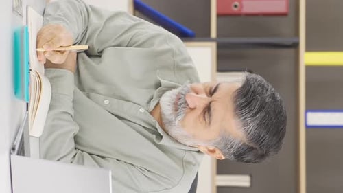 Man Works At Desk Counting Money and Writing