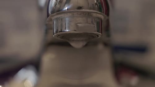 Close up water leaks out of a faucet.