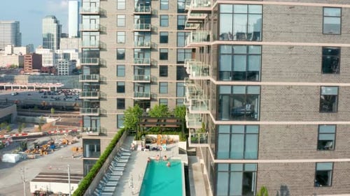 Rooftop pool at upscale residential urban apartment building in USA city. Rising aerial.