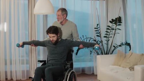 Young Man Exercising With Senior Helper in Wheelchair