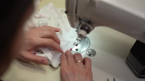 Back View From Shoulder of Skilled Craftsperson Using Industrial Sewing Machine Guiding Floral