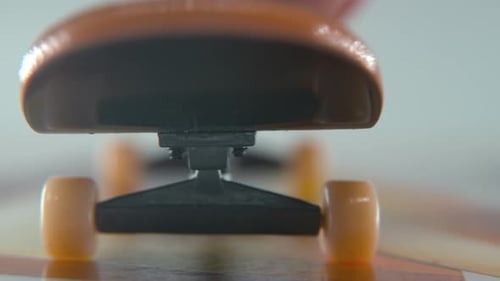 A hyper close-up detailed shot of a mini skateboard, tiny white wheels, riding fingerboard, finger s