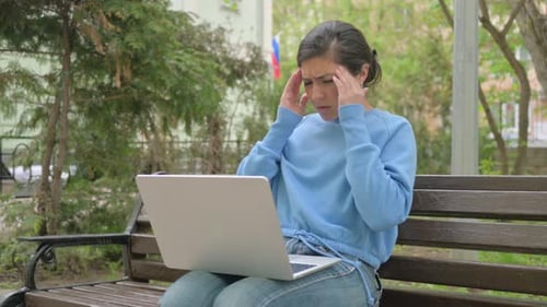 Stressed Woman Working on Laptop in Urban Park