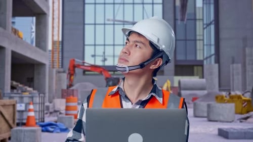 Nahaufnahme eines asiatischen männlichen Ingenieurs, der auf einer Baustelle an einem Laptop arbeitet