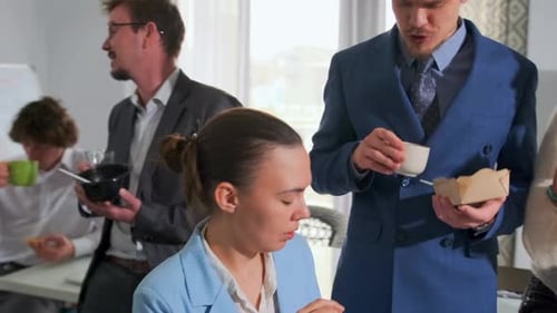 Business Team Eating Sandwiches and Drinking Coffee During Office Lunch Break