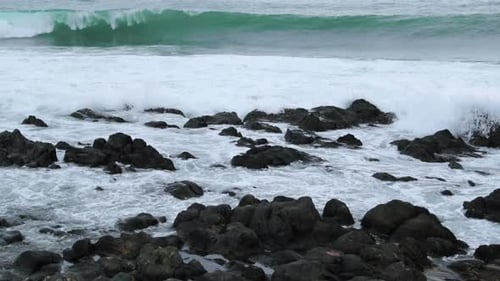 Close-up view of rocks offshore crashed by strong sea waves and reflecting on and across stones duri